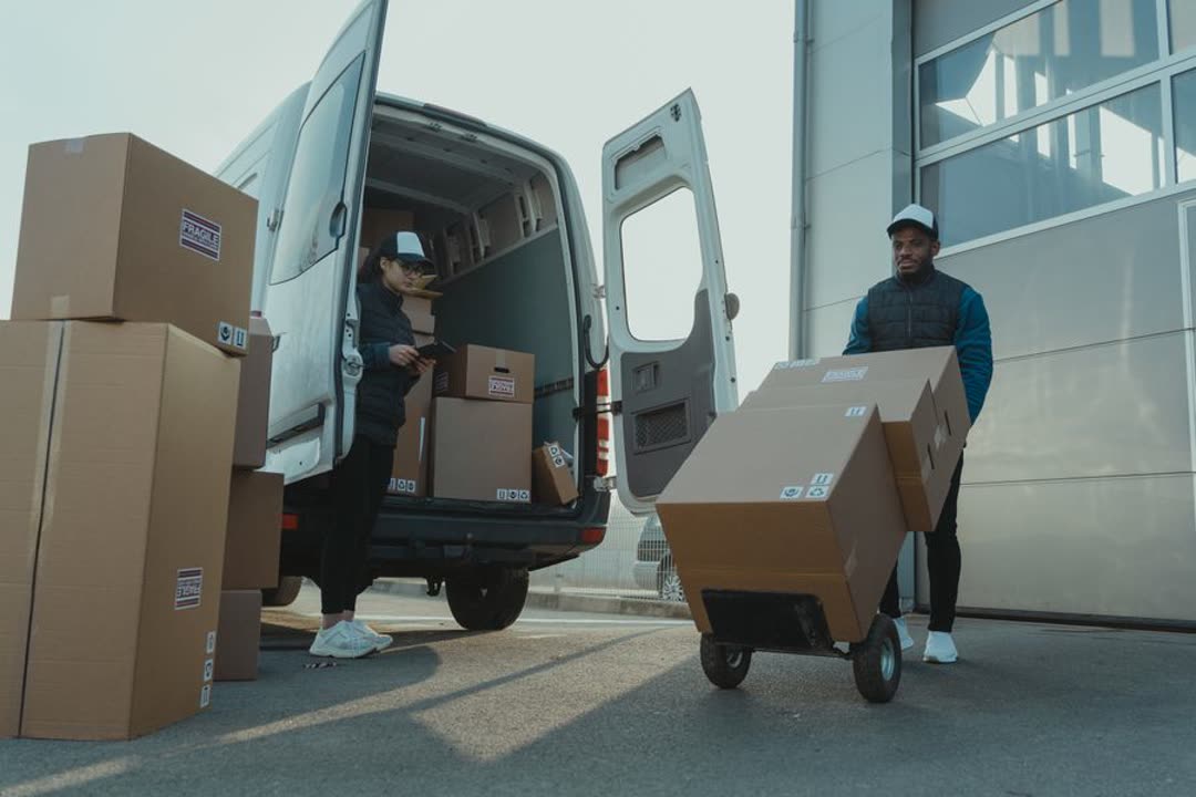 Zwei Personen verladen Versandkartons an einem Lieferwagen